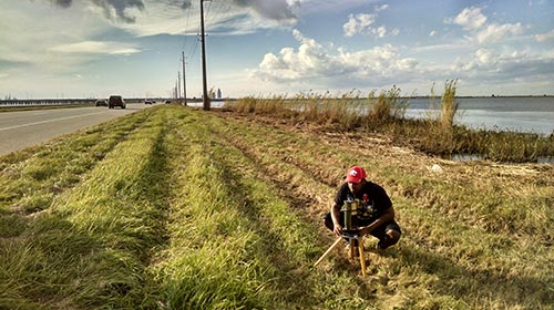 Student working on land beside Mobile Bay,