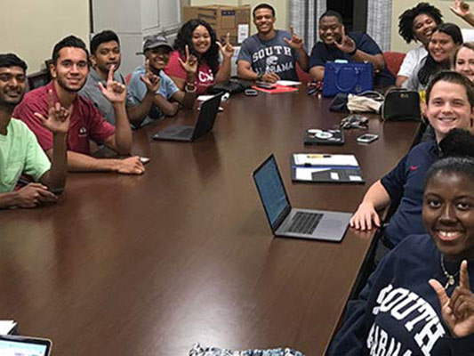 RA staff at table holding up J sign