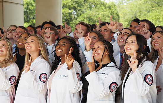 Medical students in whitecoats holding up the J sign for Jaguars.